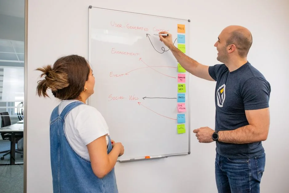 Un groupe réuni pour une réunion d’affaires, analysant des graphiques sur des ordinateurs portables et des documents.